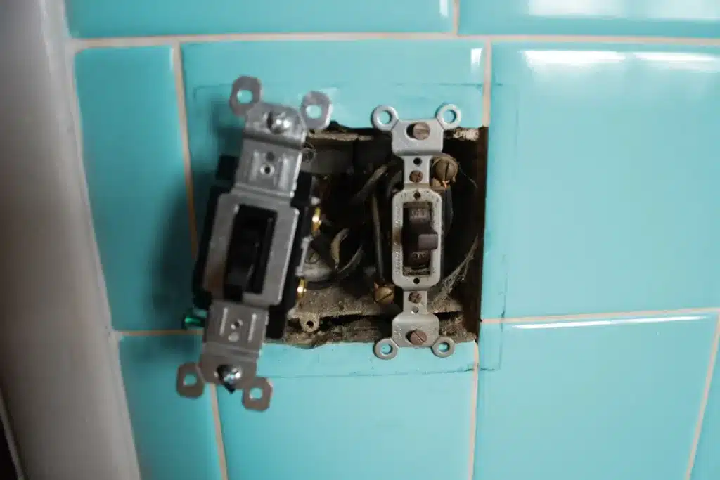 Old, faulty electrical switches on a tiled wall. Time for switch replacement!
