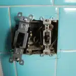 Old, faulty electrical switches on a tiled wall. Time for switch replacement!