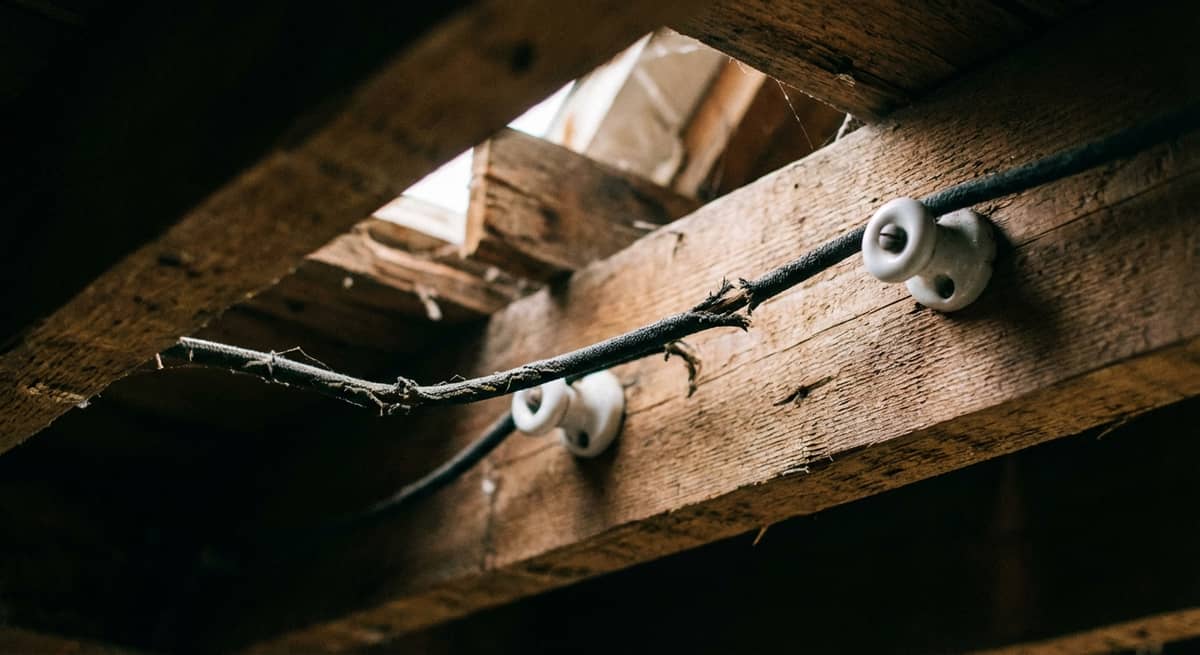 Vintage ceramic knob and tube wiring attached to wooden attic joists